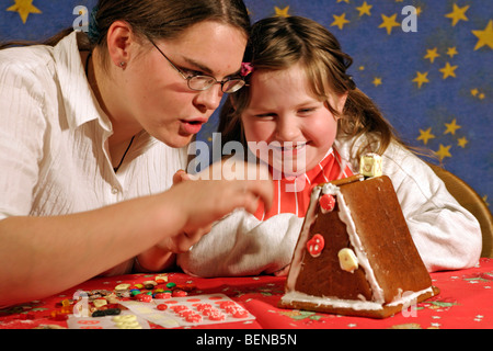 ein kleines Mädchen und ihre große Schwester ein kleines Haus aus Süßigkeiten machen Stockfoto