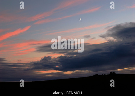 Leedon Tor in der Dämmerung mit roten Wolkenfetzen und New Moon, Dartmoor, Devon, England, UK Stockfoto