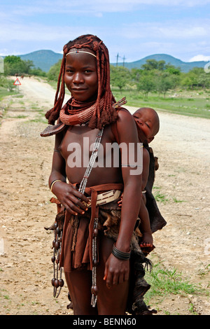 Himba-Frau mit Kind auf dem Rücken, Kaokoland / Kaokoveld, Kunene-Region, nördlichen Namibia, Südafrika Stockfoto