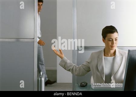 Geschäftsfrau sitzen am Schreibtisch arbeiten, deutete für Mann ins Büro Stockfoto