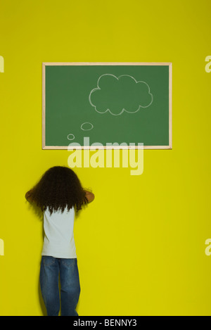 Kleines Mädchen vor Wand, dachte Blase an Tafel Stockfoto