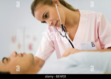 Krankenschwester, die Brust des männlichen Patienten mit Stethoskop hören Stockfoto