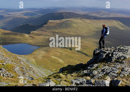 Eine weibliche Hügel Walker bewundert die Aussicht von Aran Fawddwy in Snowdonia, Nordwales. Unterhalb liegt der See Creiglyn Dyfi. Stockfoto