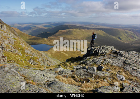 Eine weibliche Hügel Walker bewundert die Aussicht von Aran Fawddwy in Snowdonia, Nordwales. Unterhalb liegt der See Creiglyn Dyfi. Stockfoto