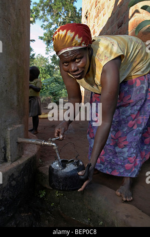 UGANDA im Hause des Najjemba Teopista, Kasaayi Dorf, Kayunga Bezirk. Teopista unter Wasser von Regentank. Stockfoto