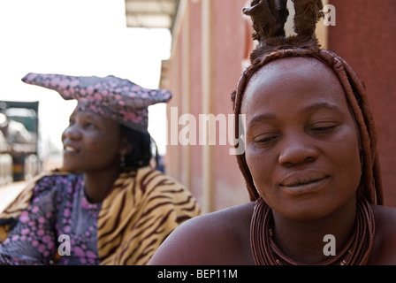 Himba und Hererowomen in einem Dorf in der Nähe von Epupa Wasserfälle, Namibia, Afrika. Stockfoto