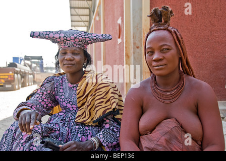 Himba und Hererowomen in einem Dorf in der Nähe von Epupa Wasserfälle, Namibia, Afrika. Stockfoto