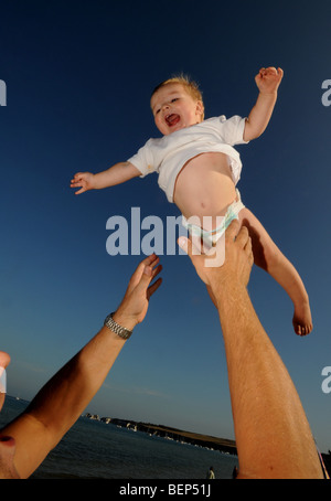 Ein Vater mit seinem Baby am Strand an einem schönen Sommertag in England spielen Stockfoto