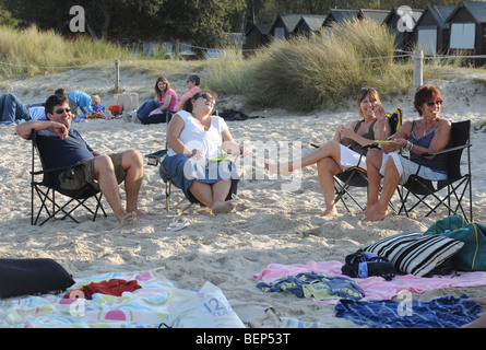 Familie sitzt am weißen Sandstrand genießen die britische Sommerzeit in Dorset, England Stockfoto