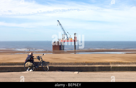 Mann mit Fahrrad auf Pipeline Repair Plattform am Strand Stockfoto