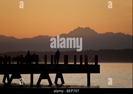 Auf Alki Beach in West Seattle, Washington geht die Sonne über die Olympic Mountains und Bainbridge Island. Stockfoto