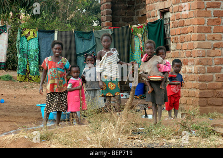 Schwarze Kinder posieren vor Wäsche trocknen auf der Wäscheleine im Dorf in Sambia, Südafrika Stockfoto
