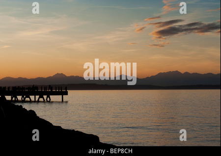 Auf Alki Beach in West Seattle, Washington geht die Sonne über die Olympic Mountains und Bainbridge Island. Stockfoto