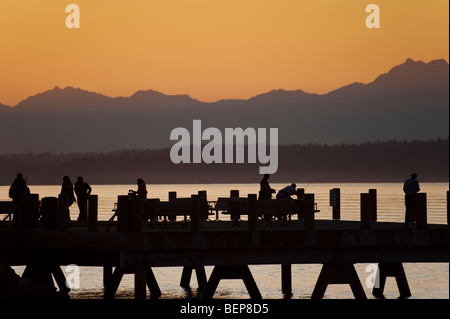 Auf Alki Beach in West Seattle, Washington geht die Sonne über die Olympic Mountains und Bainbridge Island. Stockfoto