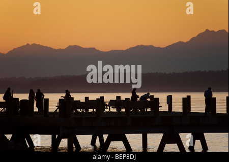 Auf Alki Beach in West Seattle, Washington geht die Sonne über die Olympic Mountains und Bainbridge Island. Stockfoto