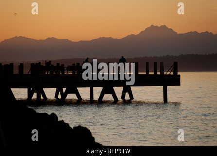 Auf Alki Beach in West Seattle, Washington geht die Sonne über die Olympic Mountains und Bainbridge Island. Stockfoto