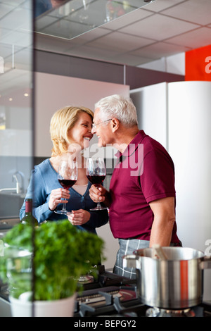 Älteres Paar küssen in der Küche Stockfoto