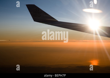 Flugzeugflügel vor einem dramatischen Sonnenuntergang Dämmerung Himmel Stockfoto