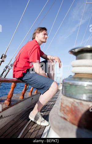 Mann sitzt auf einem hölzernen Schienen Stockfoto