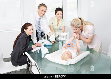 Eine Mutter, die ein Baby in einer Besprechung ändern Stockfoto