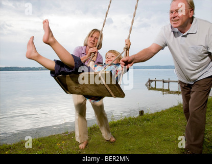 Großeltern mit Enkel auf Schaukel Stockfoto