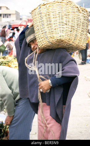 Mann mit riesigen schweren Weidenkorb ausgewogen auf seiner Schulter. Lokalen Markt Hochland Ecuadors Stockfoto