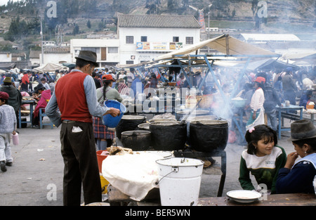 Männliche Stall Besitzer halten Kunststoff Eimer und Umfragen Linie von tief Metall Kessel wie Töpfe auf gekochten Garküche.  Ecuador-Markt Stockfoto