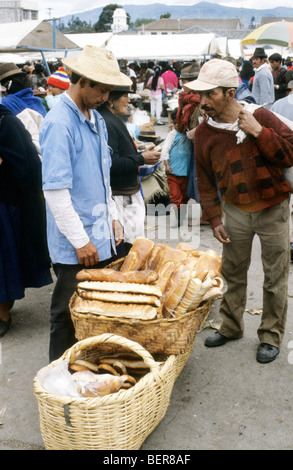 Mann mit Stroh Hut steht vor großen Korb voller lange leicht abgeflacht Brote.  Ecuadorianische Hochland Markt. Stockfoto