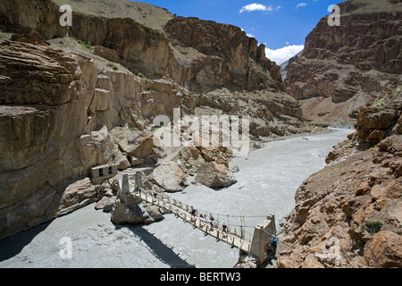 Wanderer, die über eine Brücke über den Fluss Shadi. In der Nähe von Phugtal Kloster. Zanskar. Indien Stockfoto