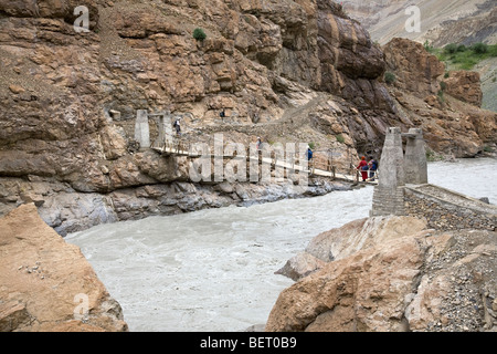 Wanderer und Mönch, die über eine Brücke über den Fluss Shadi. In der Nähe von Phugtal Kloster. Zanskar. Indien Stockfoto