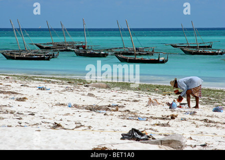 Traditionelle hölzerne Fischerboote und Beachcomber Suche am weißen Strand entlang des Indischen Ozeans, Sansibar, Tansania, Afrika Stockfoto