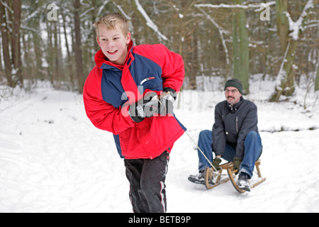 kleiner Junge seinem Vater auf einem Schlitten ziehen Stockfoto