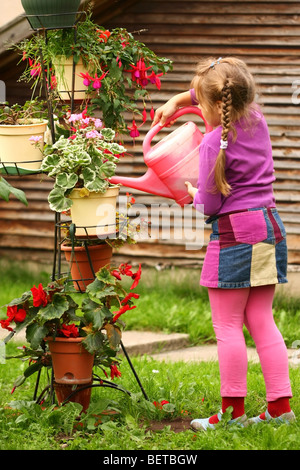 Kleines Mädchen Blumen im Garten gießen Stockfoto