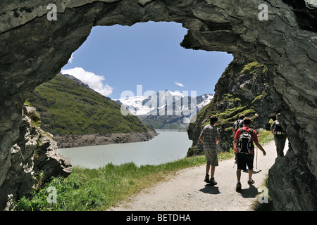 Touristen zu Fuß durch Höhle entlang des Lac des Dix, gebildet durch den Staudamm Grande Dixence, Valais / Wallis, Schweizer Alpen, Schweiz Stockfoto