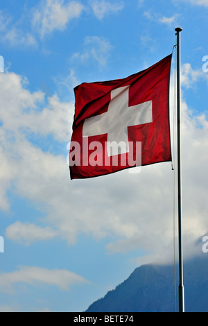 Schweizer Fahne flattert im Wind gegen bewölktem Himmel, Schweiz Stockfoto