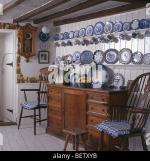 Sammlung von blaue + weiße Porzellanteller in Regalen auf weißen getäfelte Wand über dem antiken Schrank im Landhaus Esszimmer Stockfoto