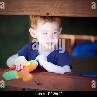 Junge in Holz Spiel Fort mit Spielzeugpistole Stockfoto