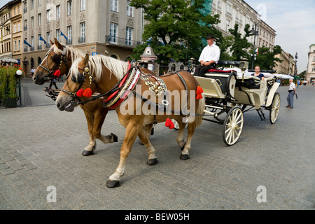 Pferdekutsche mit touristischen Passagieren rund um den Hauptmarkt / Markt Platz. Krakau. Polen. Stockfoto