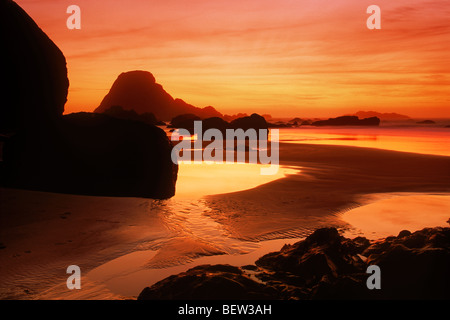 Bandon Strand entlang Coquille Fluß zwischen gemalten Himmel Sonnenuntergang und Gezeiten-Pools an felsigen Oregon Küste Stockfoto