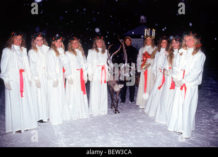 Miss Lucia Queen und Prinzessinnen im Park Skansen in Stockholm am 13. Dezember mit Rentier und Schnee fällt Stockfoto