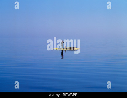 Mann und sein Hund allein mit Fernglas und Aktenkoffer und Handy auf winzigen Stockholmer Schären-Insel Stockfoto