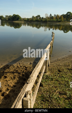 Eine Landschaft am Welford Reservoir zeigt einen alten Zaun ins Wasser gebaut. Stockfoto