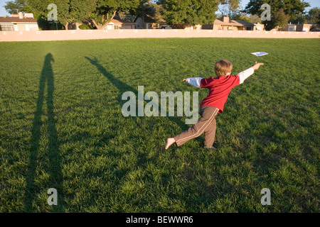 sieben Jahre alten werfen ein Papierflugzeug in einem Park, Dämmerung Stockfoto