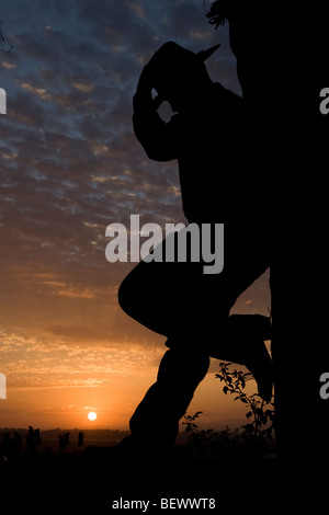 Ein Cowboy Tipps seine Cowboy-Hut, während die Sonne in der Ferne versinkt. Stockfoto