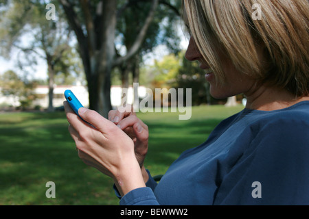 Nahaufnahme einer Frau mit ihrem i-Telefon mit Touchscreen, sitzt in einem park Stockfoto