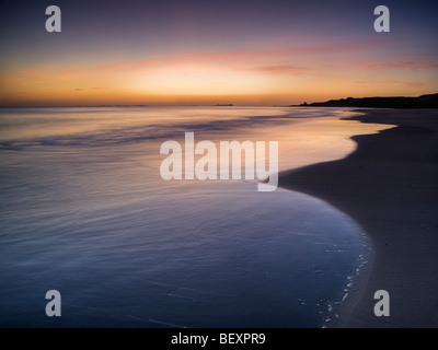 Rosa leuchtet vor der Morgendämmerung das Meer an der Bucht Budle, Northumberland Stockfoto