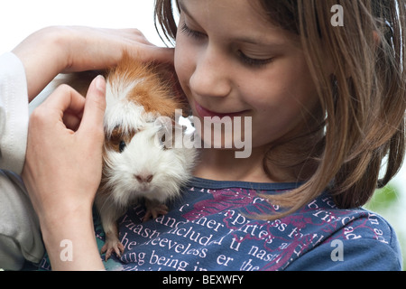 eine Mädchen ist mit ihrem Meerschweinchen knutschen. Stockfoto