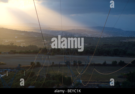 Sonne glitzerte aus Pylon Stromkabel erstreckt sich über die Landschaft in die Ferne Stockfoto