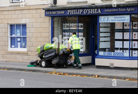 Operativen mit einen Spaziergang hinter Bürgersteig und Straße Kehrmaschine auf dem Bürgersteig in Devizes Stadtzentrum Wiltshire England UK Stockfoto