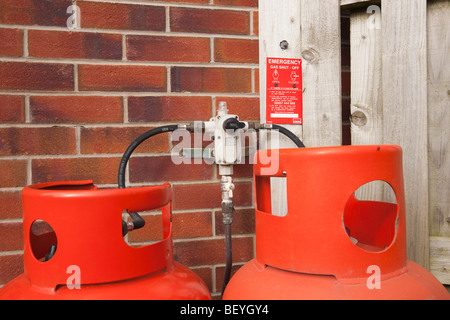 England, UK. Calor Gaszylinder und zwei Schlauch-Regulierventil Montage an einer Hauswand mit Notfall Gas abgeschaltet Anweisungen. Stockfoto